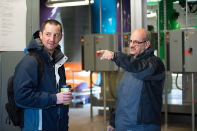 One person points something out to another in a past tour of the Geothermal Pumphouse