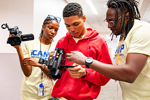 iCamp students looking at footage on a video camera
