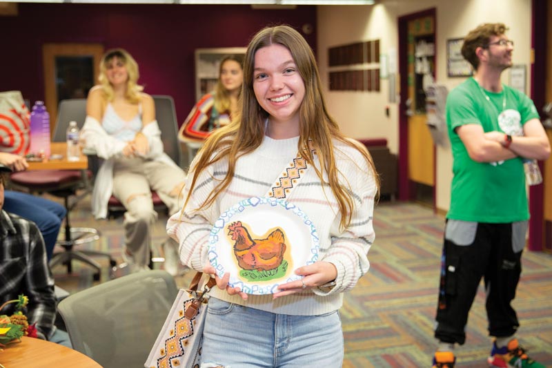 wcu student holds a paper plate with an image of a chicken