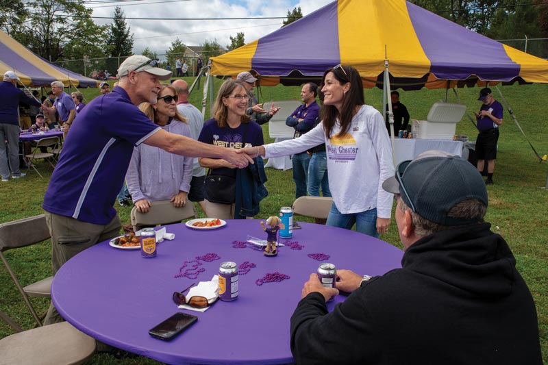 a meeting of wcu vistors around a purple table, 2 people are shaking hands
