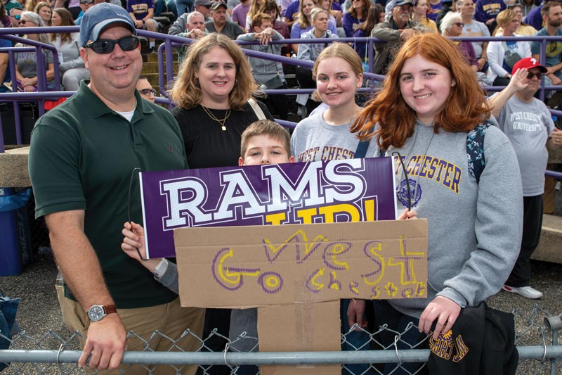 4 wcu homecoming visitors hold up 2 signs saying Rams up! and Go West Chester