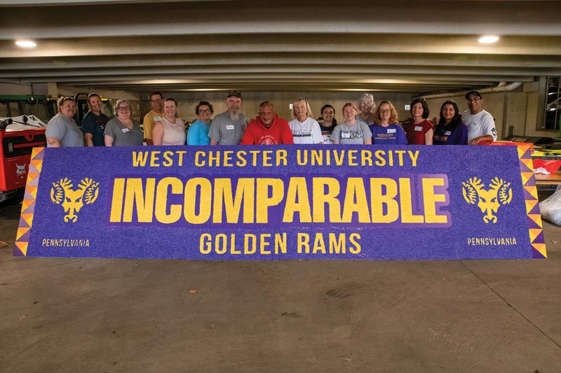 a group of people post for a picture behind a sign that says West Chester University Incomparable Golden Rams