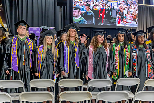 Group of students stanidng in their cap and gowns at graduation