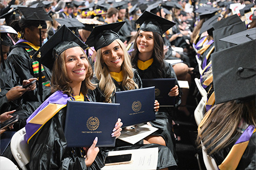 Female student sholding up their degrees at graduation